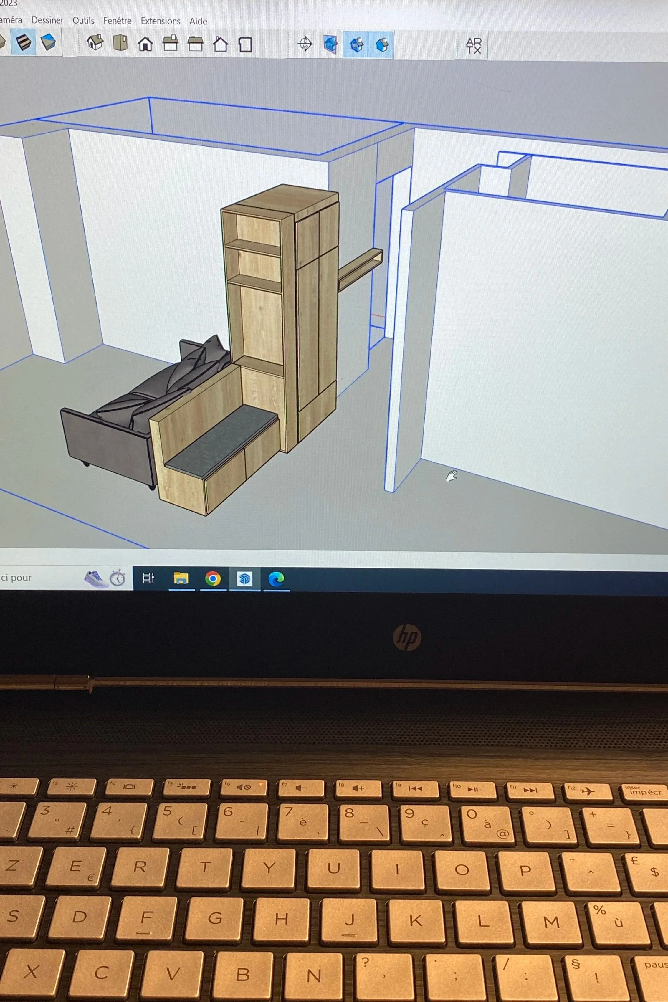 Capture d'écran d'un logiciel de modélisation 3D Sketchup affichant un arrangement de meubles comprenant un canapé, une étagère, une armoire en bois et un bureau dans un espace intérieur.