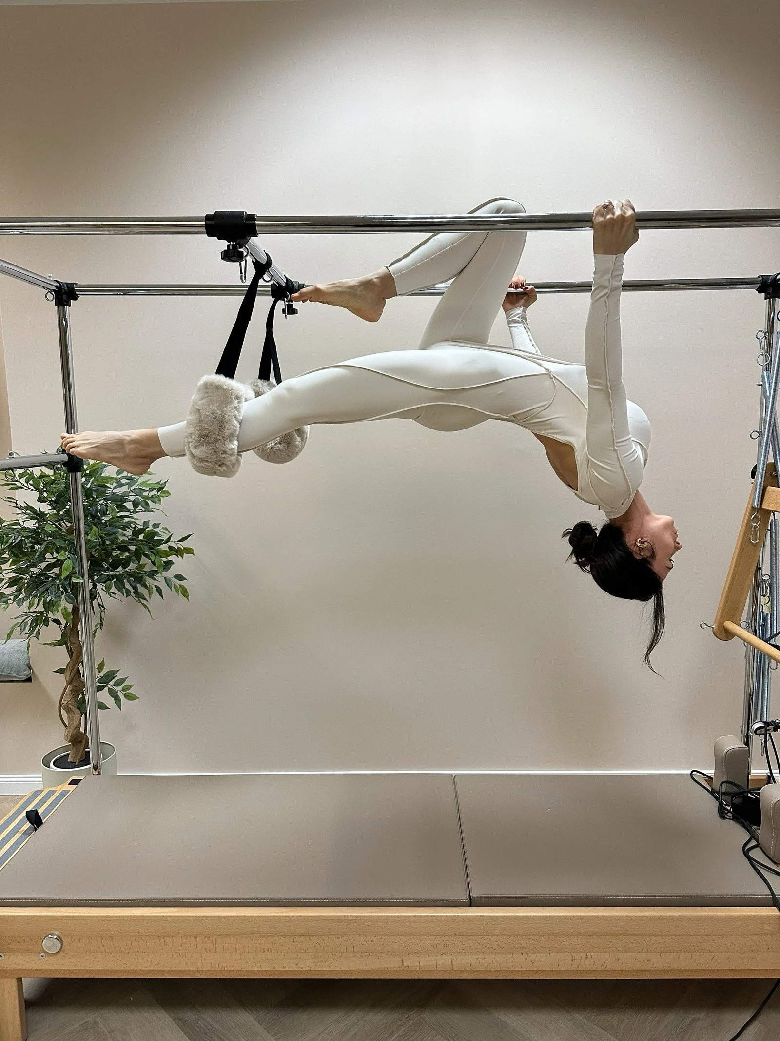 Trainerin im Reformer Pilates Studio The Core House in Braunschweig während einer Übung auf dem Cadillac