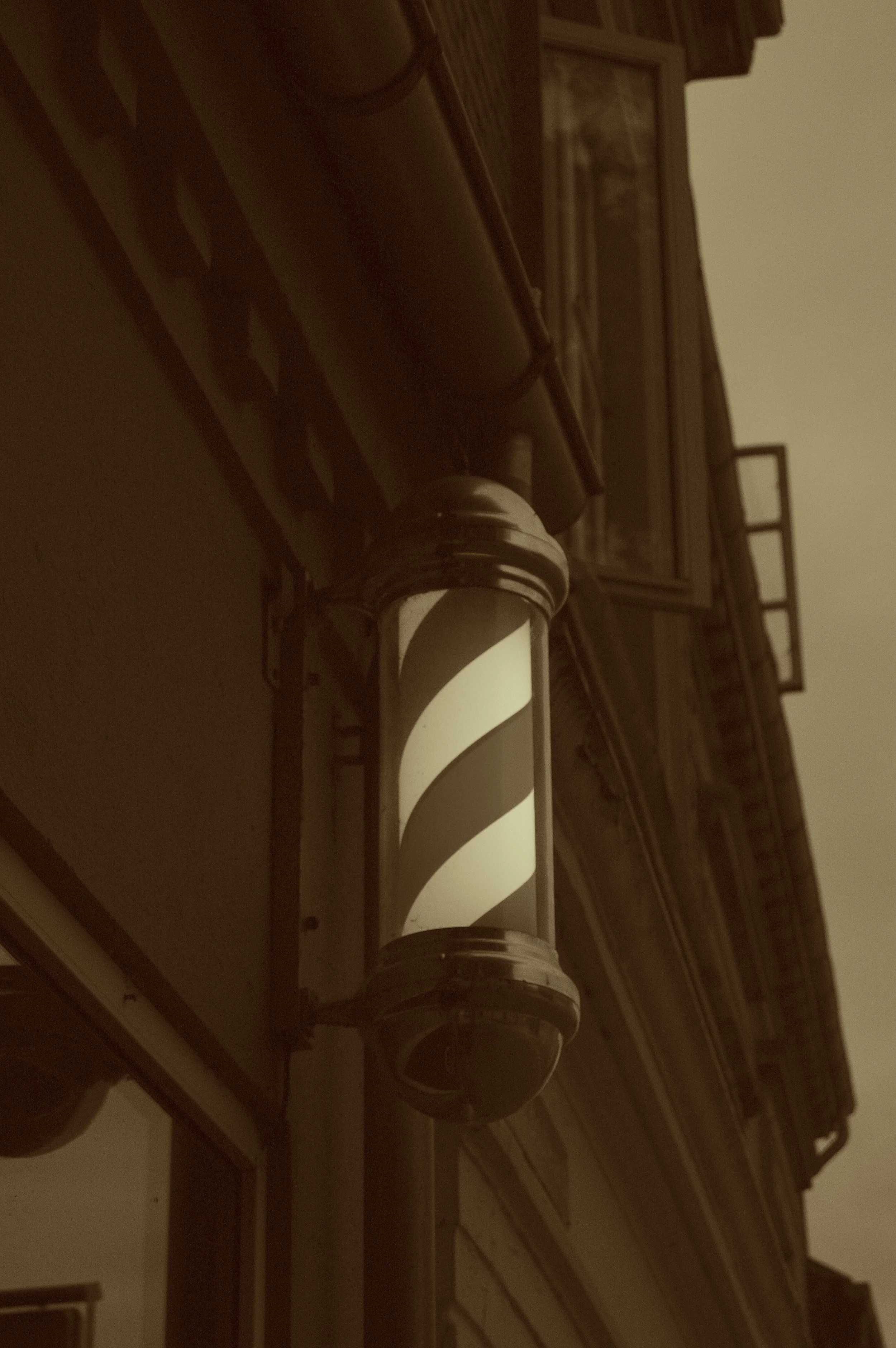 Vintage barber pole mounted on the exterior wall of a building.
