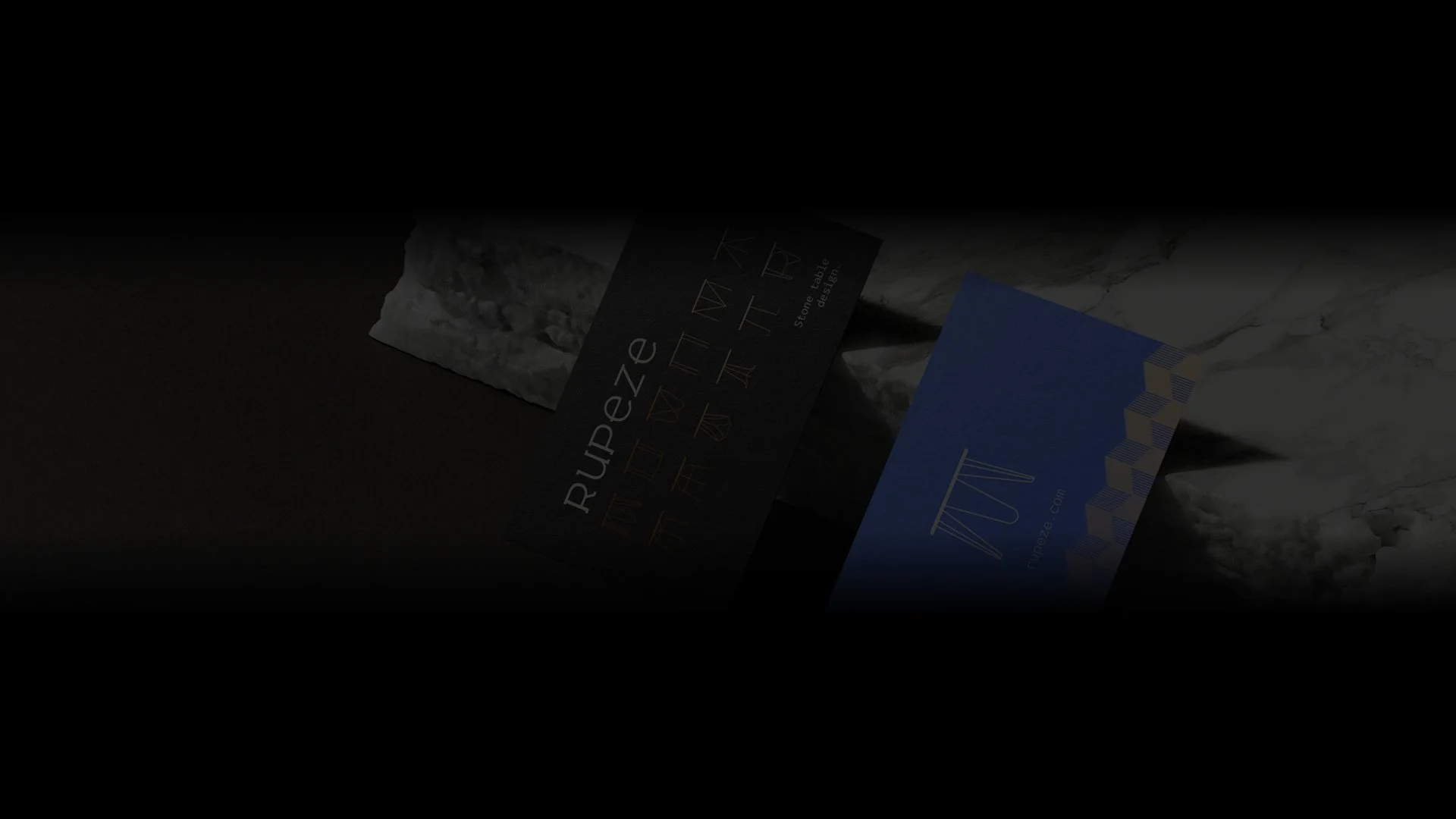 Business cards placed on a marble surface in dim lighting, featuring the text 'Rupeze' and geometric designs.