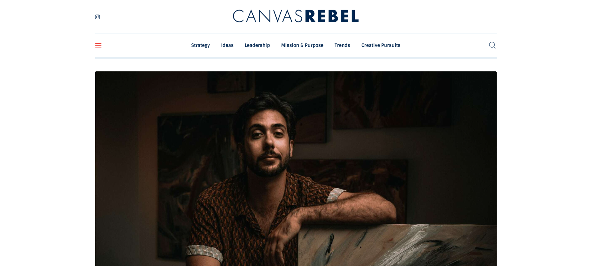Man in patterned shirt posing in a dimly lit room with paintings on the walls, part of a CanvasRebel webpage.