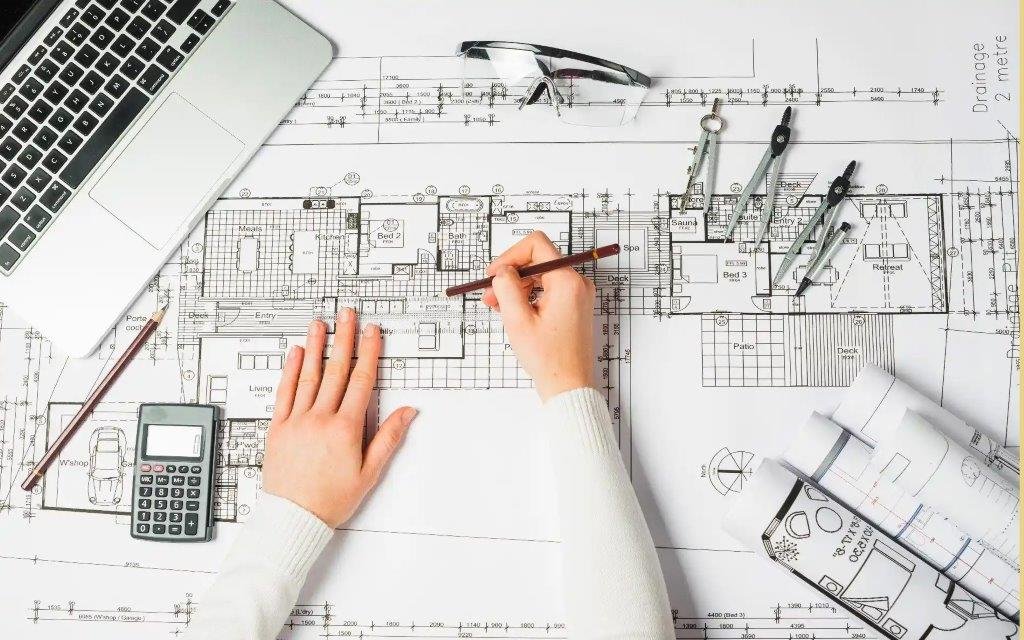 FAQ - Frequently Asked Questions - Drafting blueprint of a house with engineering tools, a laptop, and a calculator on a desk.