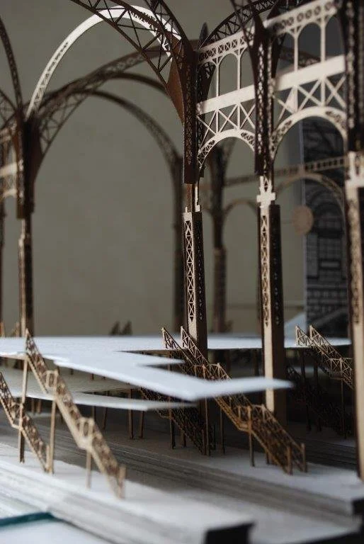 A detailed architectural model of New York's historic Penn Station with arches and stairs, made of wood or similar material.