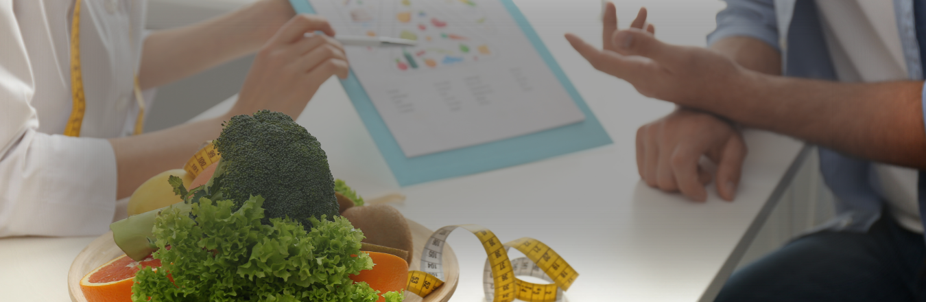 Beslenme uzmanları ve diyetisyenler danışanlarıyla toplantıda, sağlıklı beslenme planları yaparken çeşitli sebze ve meyve içeren bir tabak ile tartı ölçüleri ve belgeler kullanıyor.