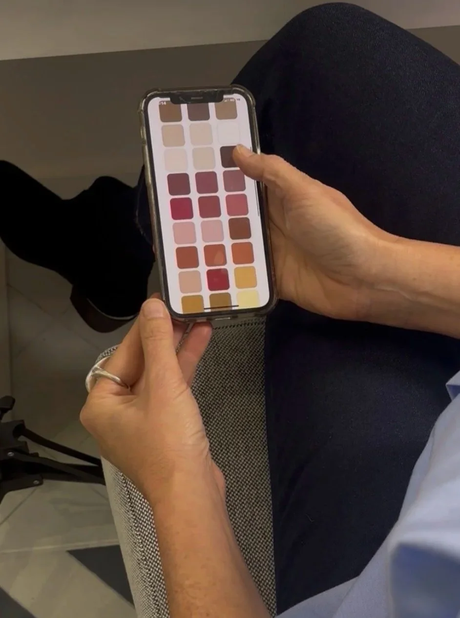 Person holding a smartphone displaying a palette of various shades of lipstick colors.