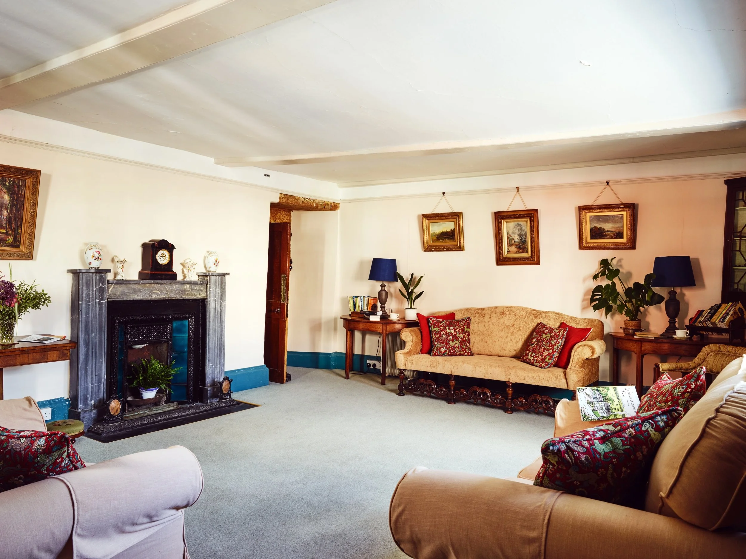 A living room with sofas, colorful pillows, a fireplace, and framed artwork on the white walls.