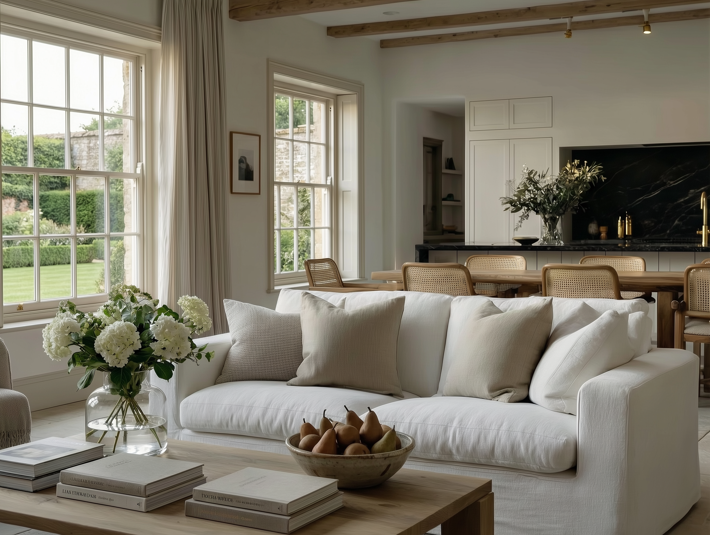 Open-plan family living area with a slouchy white linen sofa, rustic oak coffee table, and sash windows overlooking the garden.