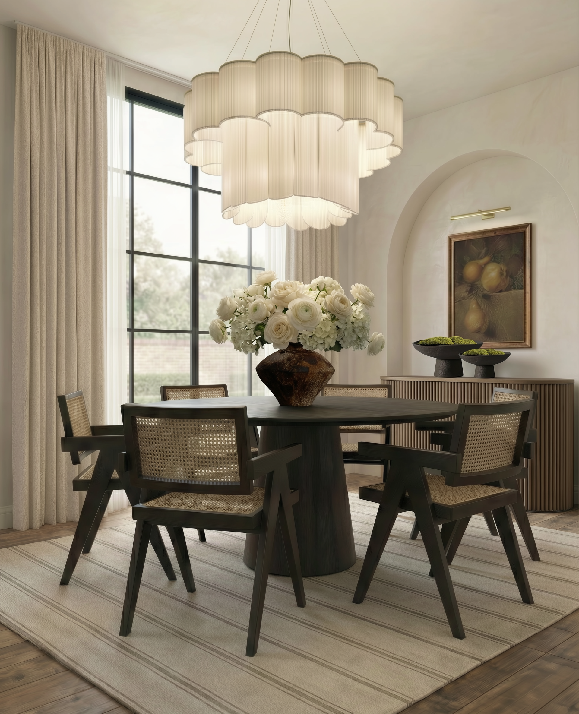 Transitional dining room in Harrogate featuring a round dark wood table, cane back dining chairs, and a statement tiered fabric chandelier for a quiet luxury feel.