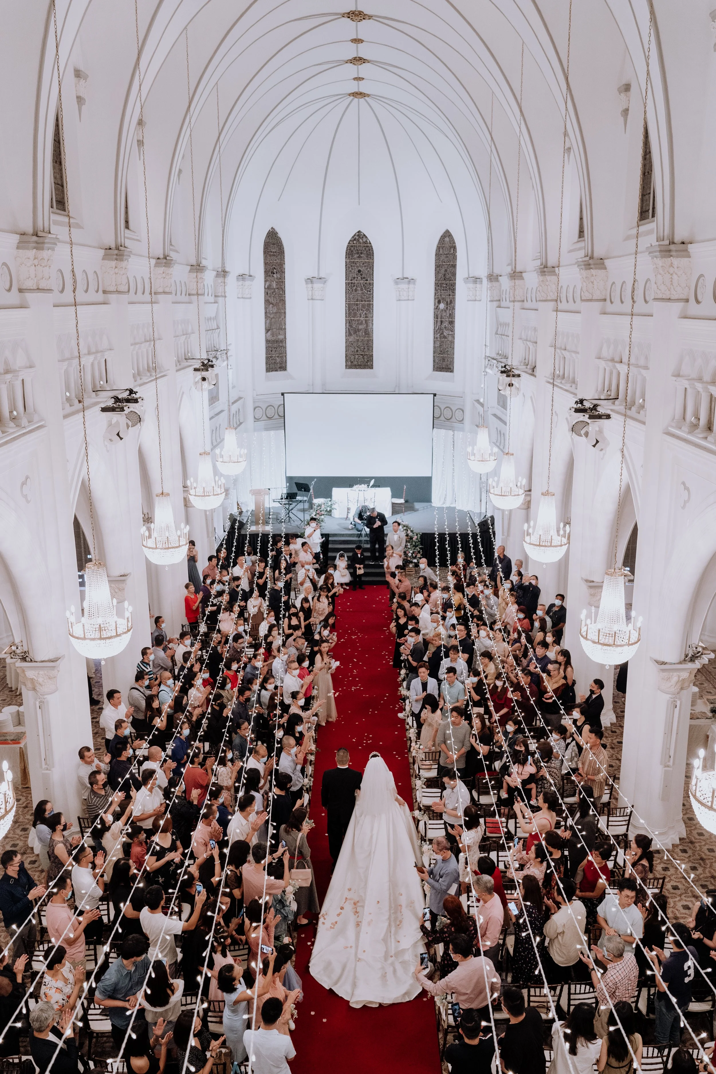 A bride and groom walking down the aisle of a church filled with seated guests during a wedding ceremony.