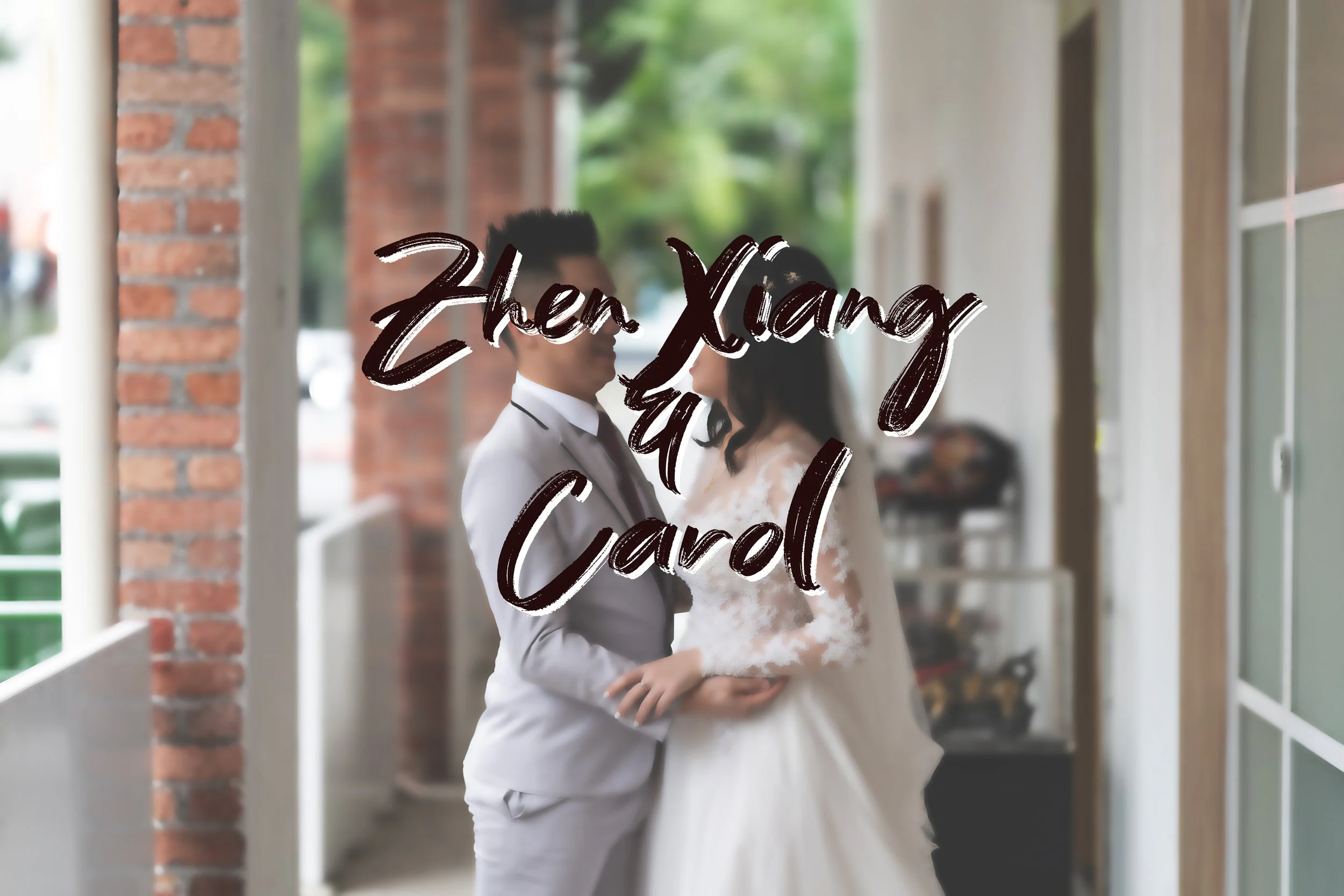 A couple in wedding attire standing close on a porch, with a brick column on the left and glass doors on the right, greenery visible in the background, and the overlay text 'Zhen Xiang & Carol'.