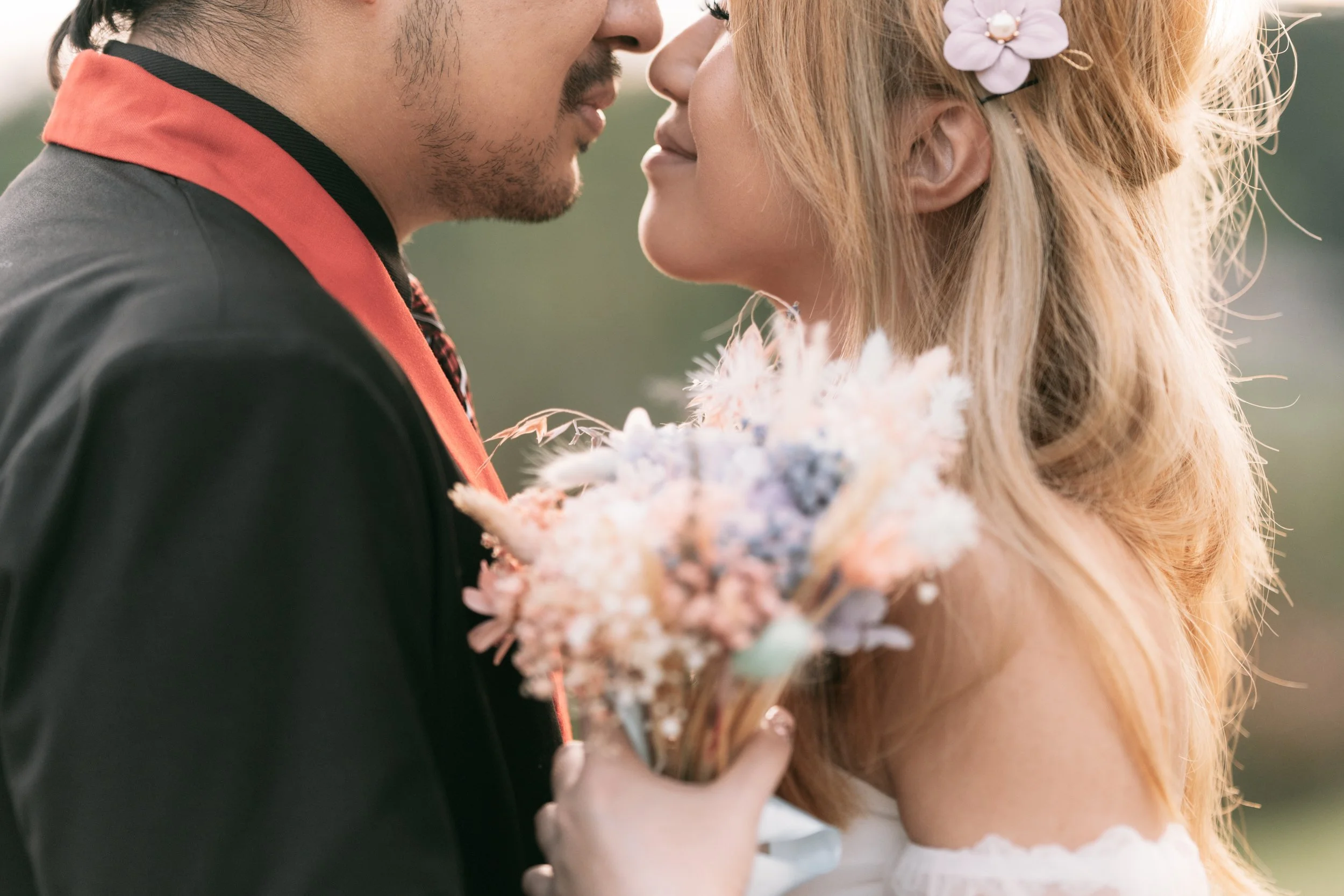 Close-up of a couple about to kiss, with the woman holding a bouquet of pastel-colored flowers.