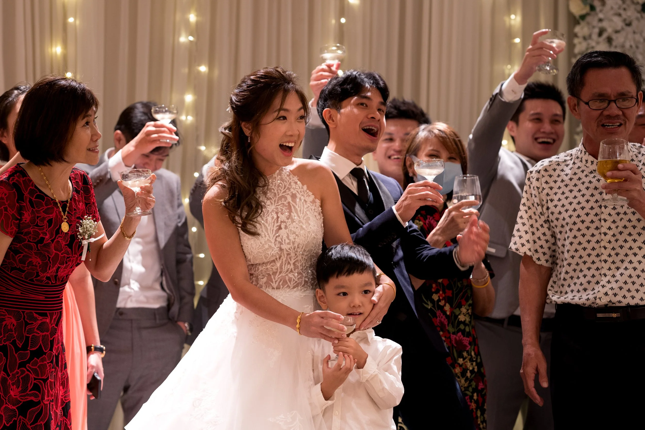 People celebrating at a wedding reception, holding drinks and smiling.
