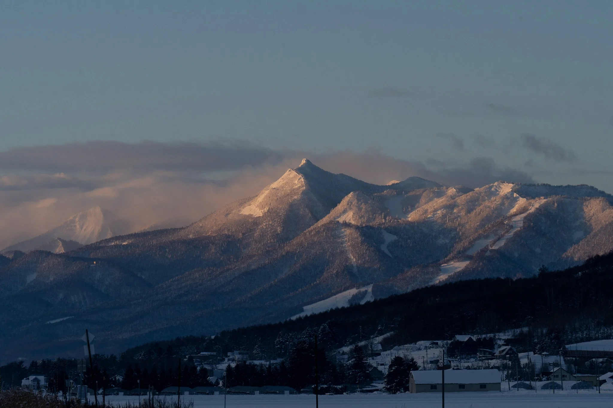 Snow-covered mountains at sunset with a small village in the foreground.