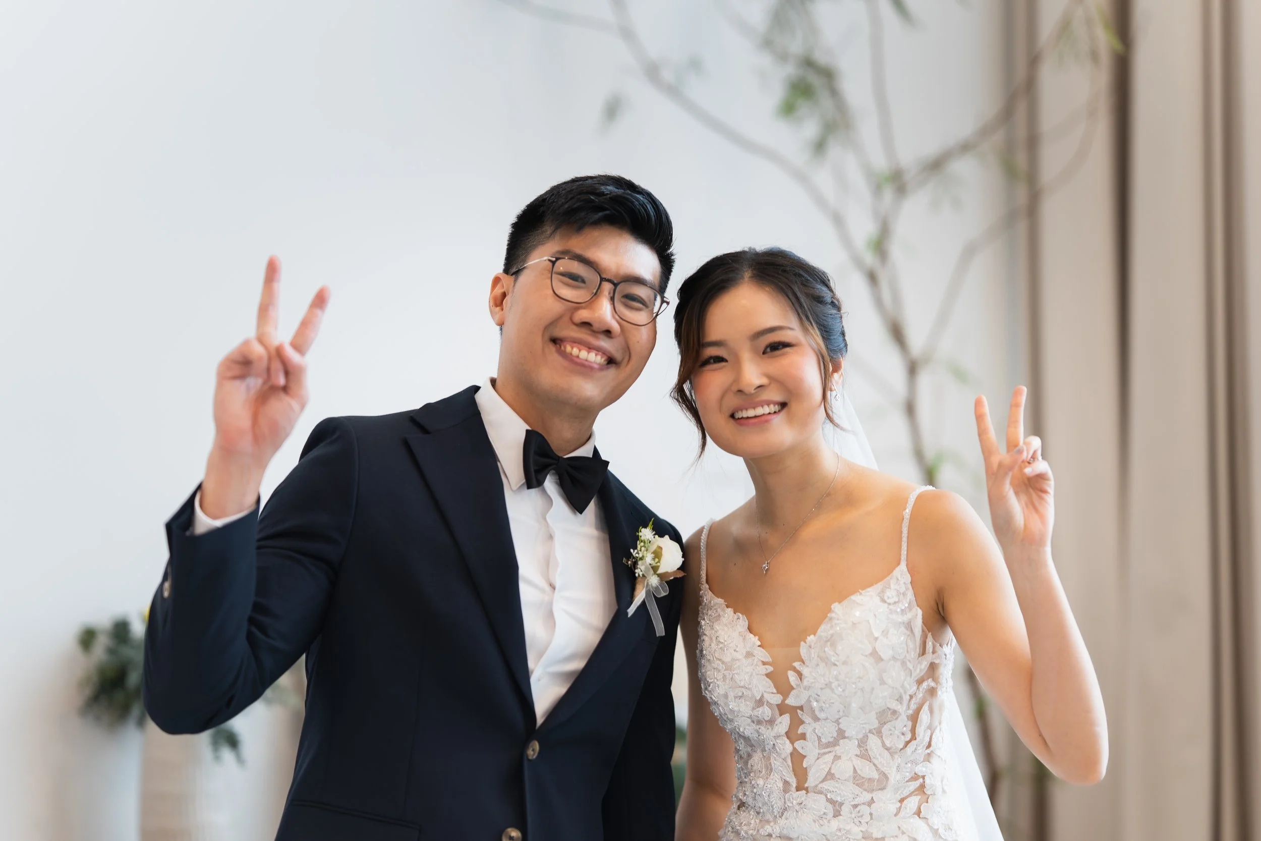 A happy couple at their wedding making peace signs for the camera.