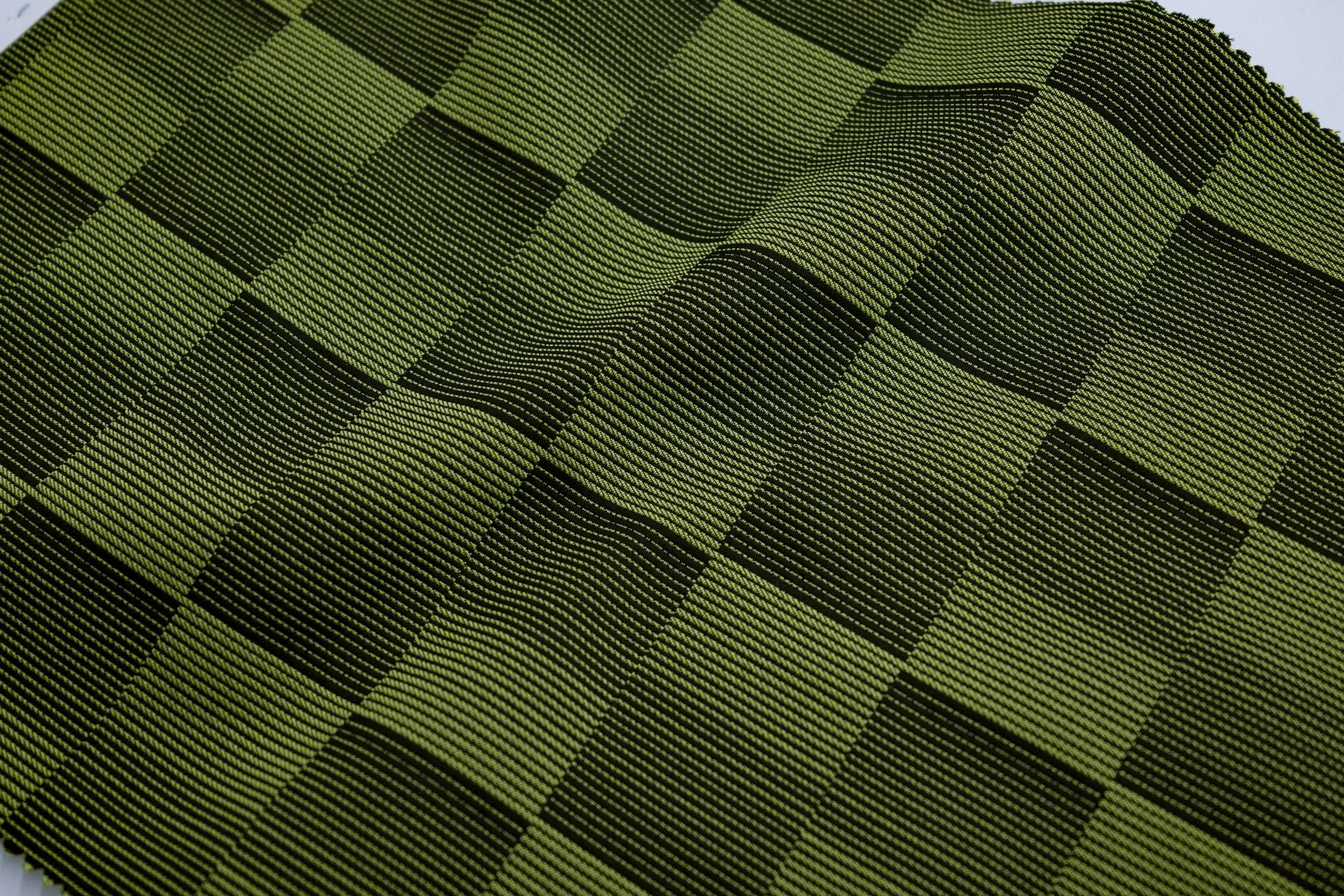 Close-up of a green and black checkered woven fabric with a textured pattern.
