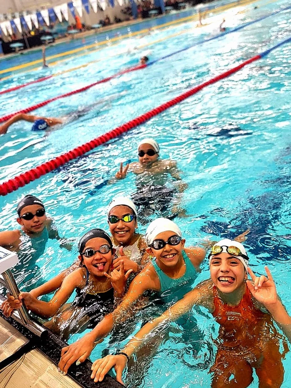 Niños en la alberca del queretaro 2000, en la copa internacional 2025 queretaro, algunos haciendo natación y otros sonriendo y haciendo gestos de amistad.