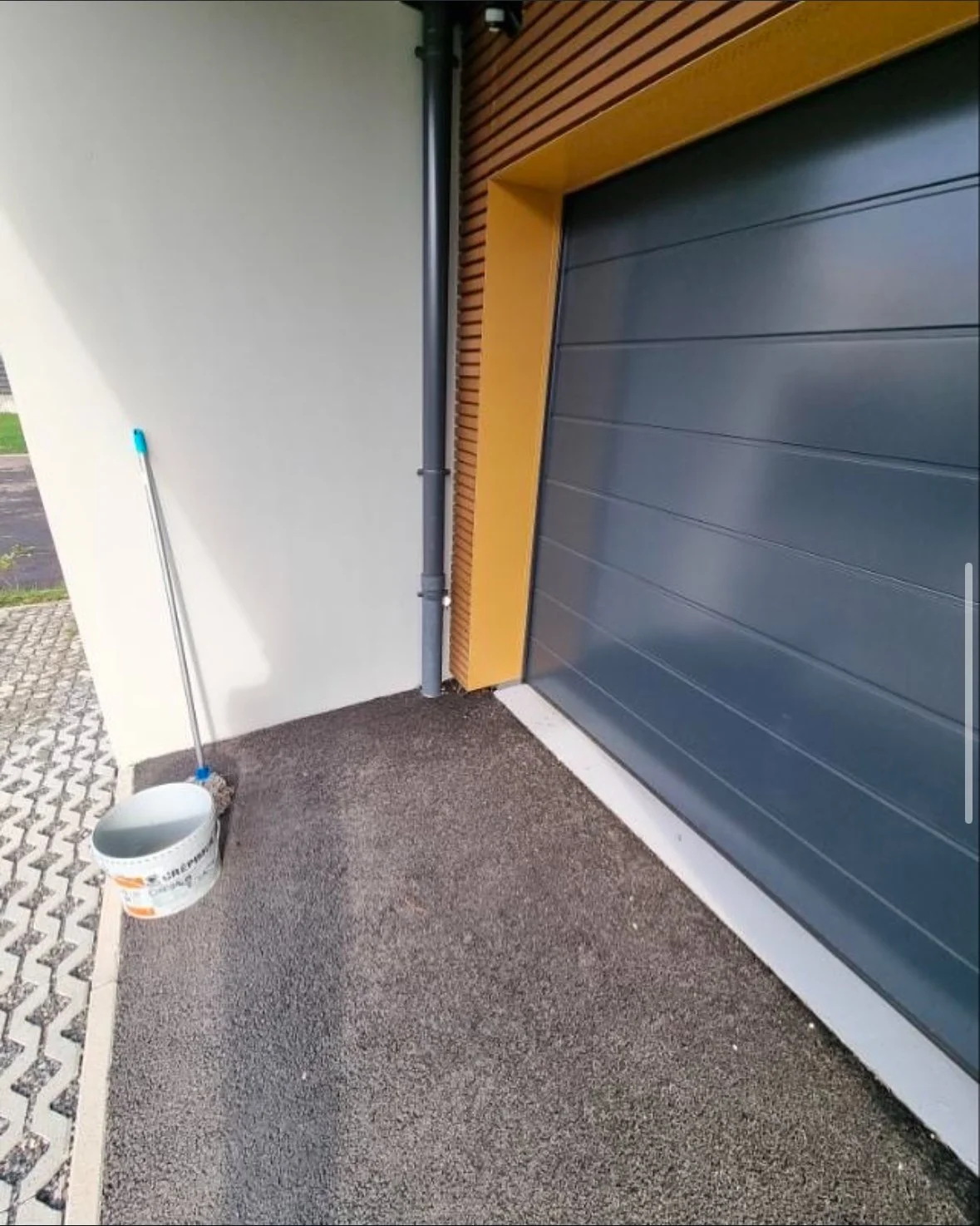 Balayeuse et seau à proximité d'un garage avec porte roulante