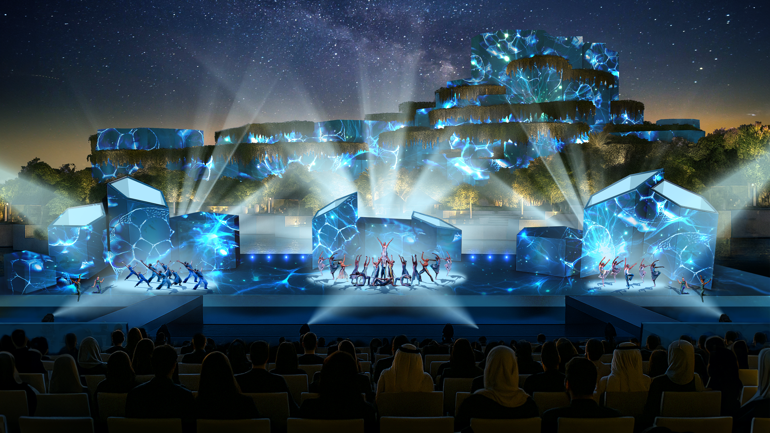 Spettacolo teatrale con luci blu e danza, pubblico seduto di fronte, sfondo di un paesaggio notturno con cielo stellato e montagna illuminata da luci e proiezioni di effetti elettrici blu.