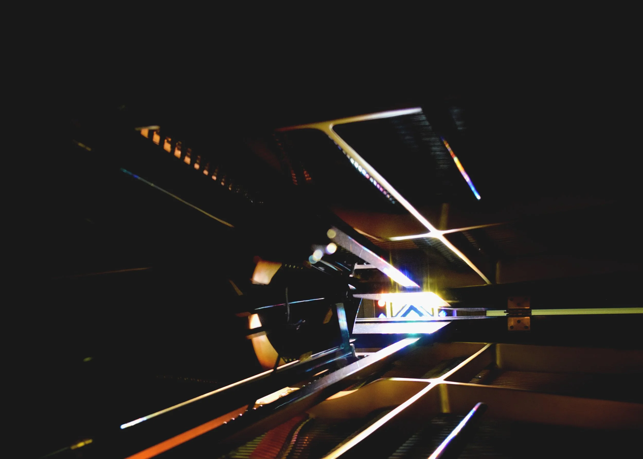 Close-up of a piano's interior strings and hammers with colorful LED lighting accents.