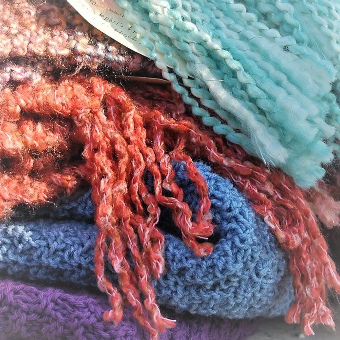 Close-up of colorful knitted and crocheted fabric, including red, blue, and purple yarns.