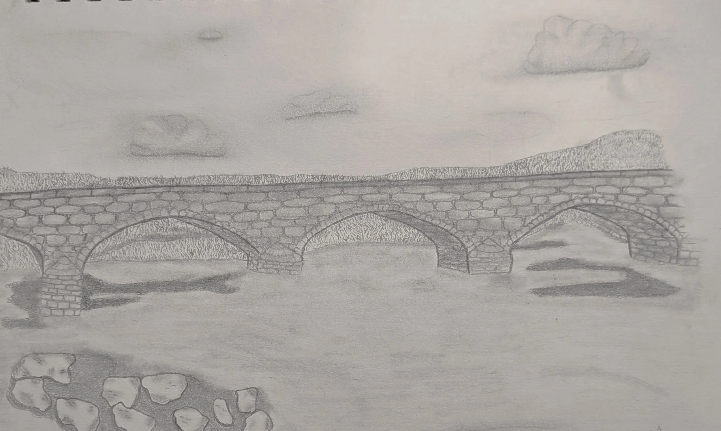 a pencil drawing of a stone bridge over a body of water with rocks in the foreground, mountains and clouds in the background
