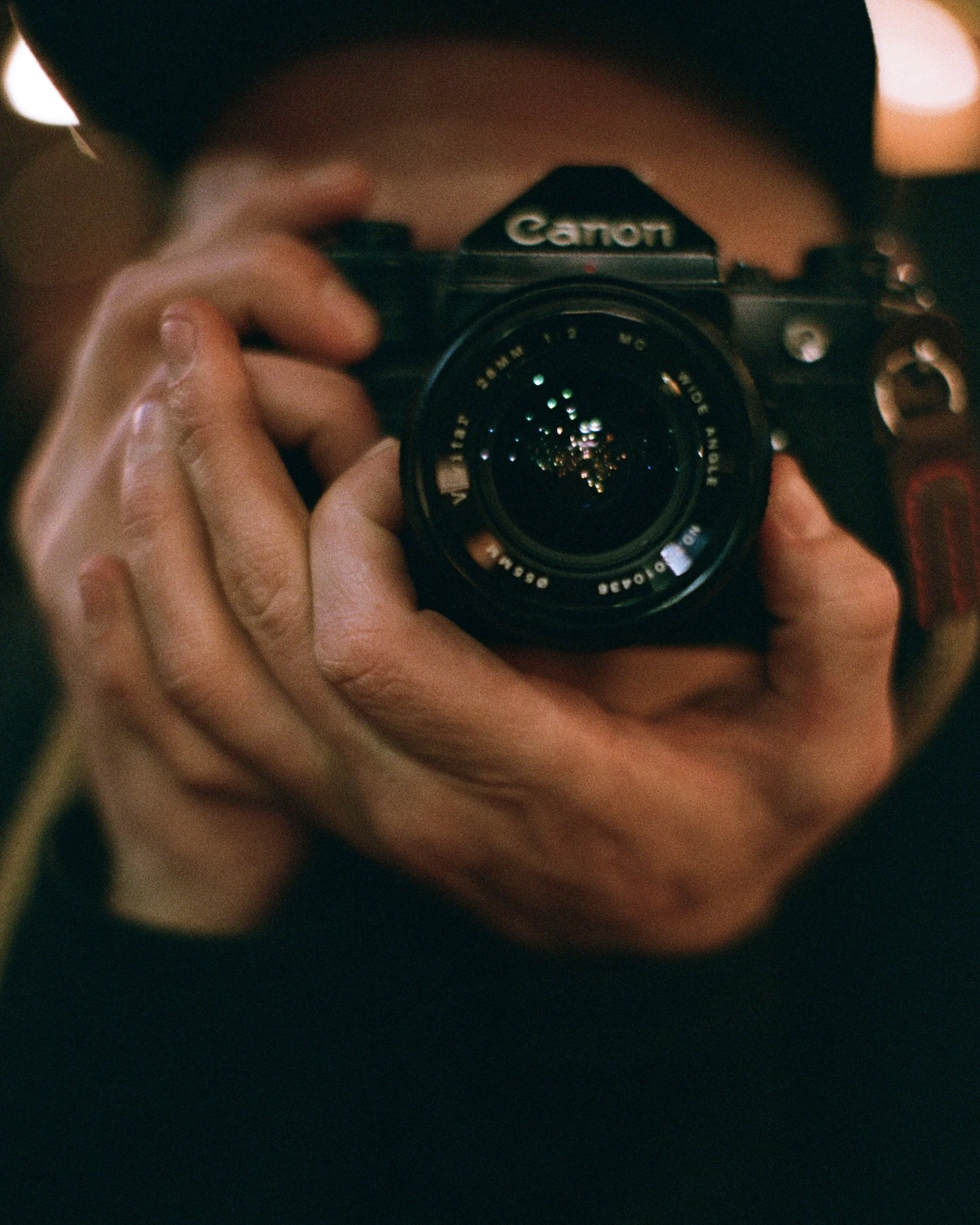 A person holding a Canon camera, taking a photograph.