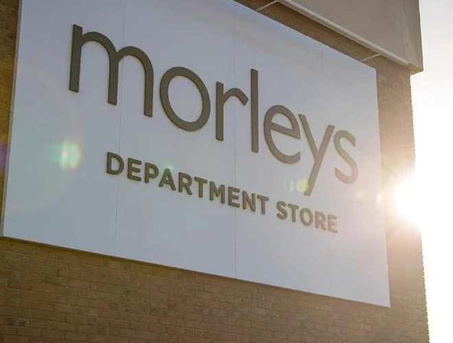 Store sign for Morley's Department Store on a building exterior, with sunlight shining from the right.