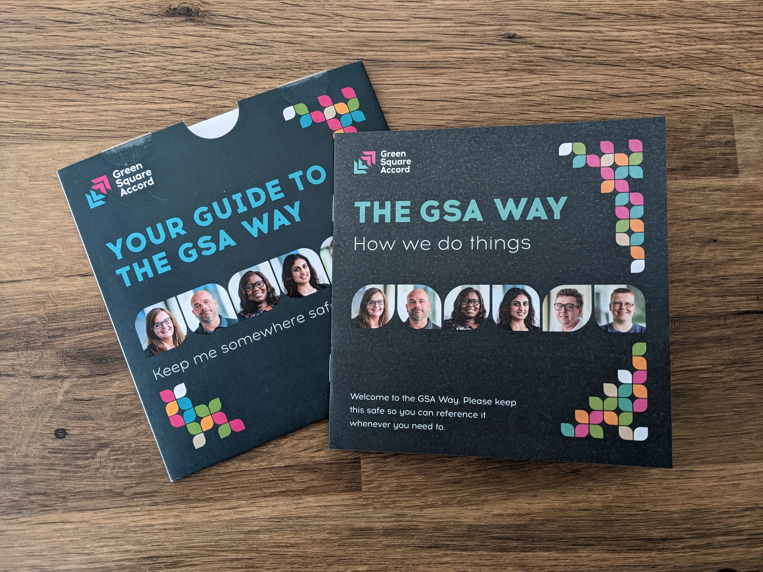 Two informational brochures about the GSA Way, featuring group photos of six diverse people, on a wooden surface.