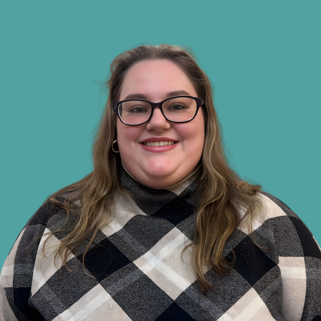 Smiling woman with long hair and glasses against a teal background.