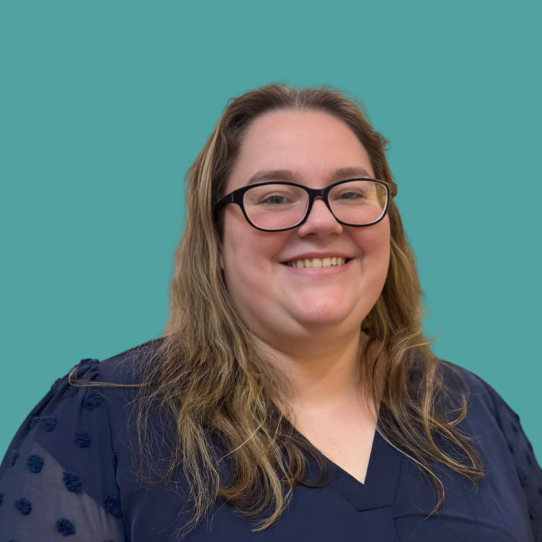 Smiling woman with long hair and glasses against a teal background.