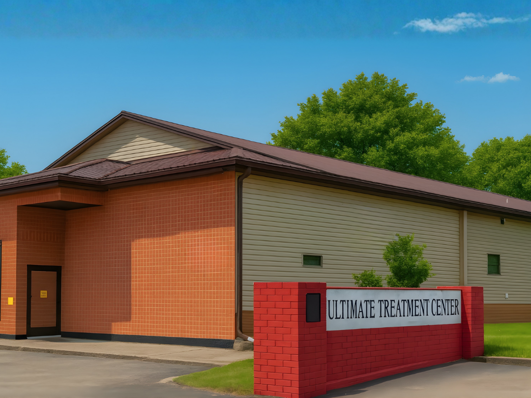 Exterior of a building labeled 'Ultimate Treatment Center' with a red brick wall and green landscaping.