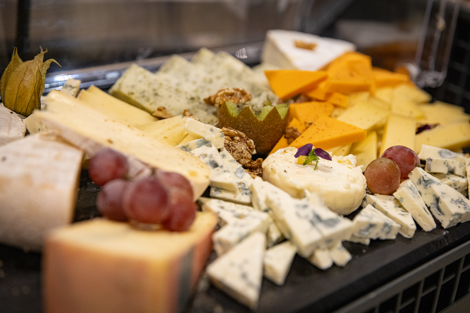 Plate de fromages variés avec raisins, noix, et garnitures, présentation appétissante.