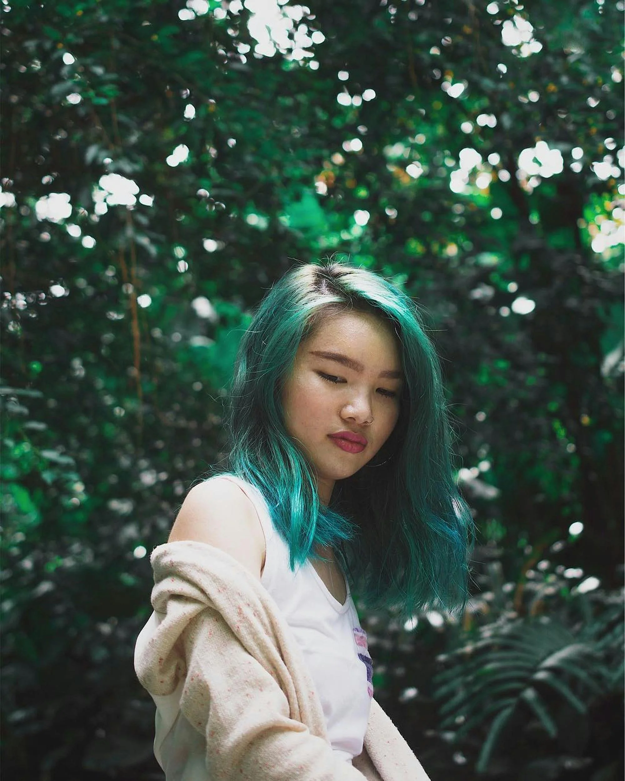 Girl with green hair in nature looking down