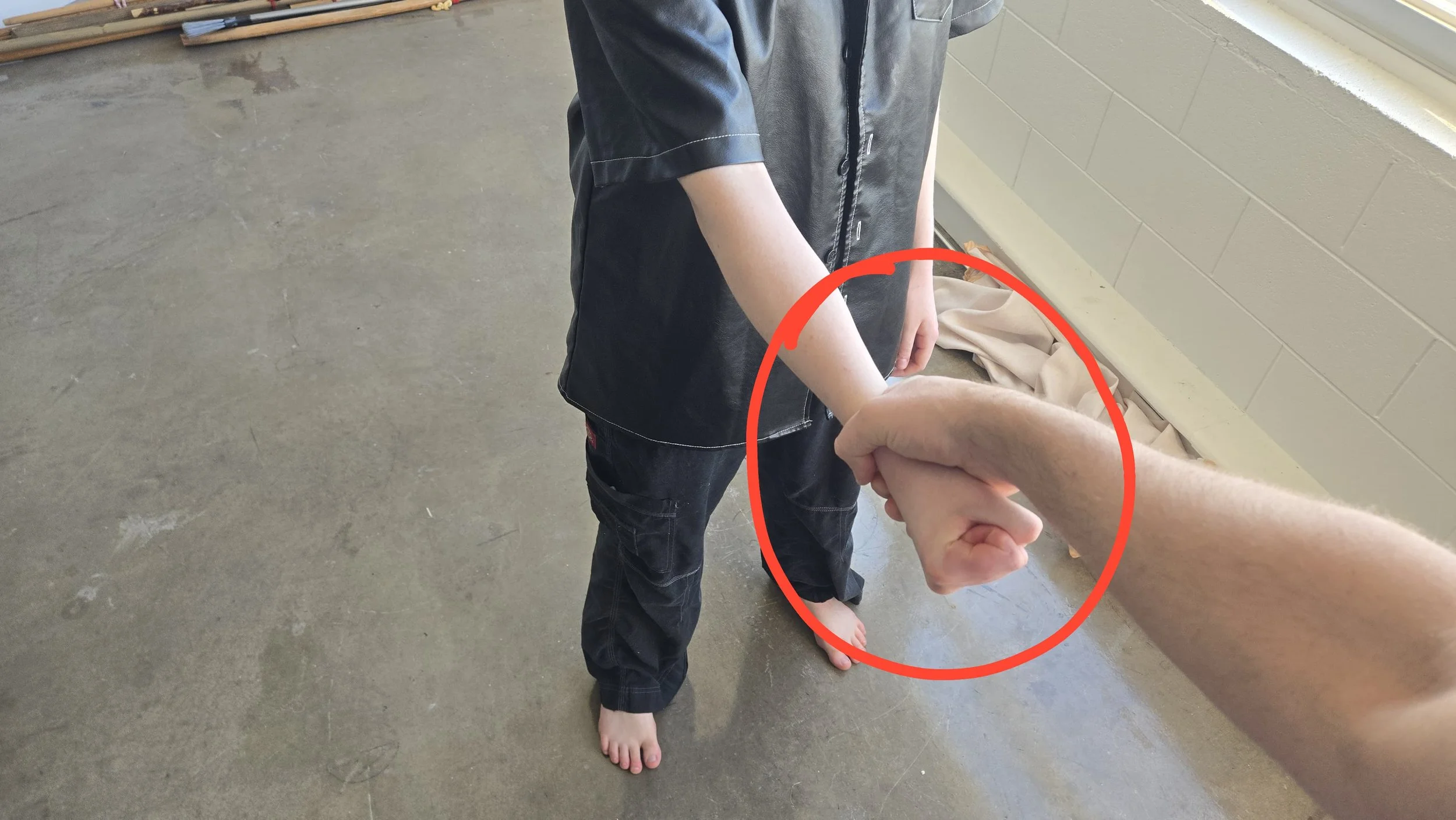 Same as the previous image, except now the hand being grabbed is closed in a tight fist. There is a red citcle around it.