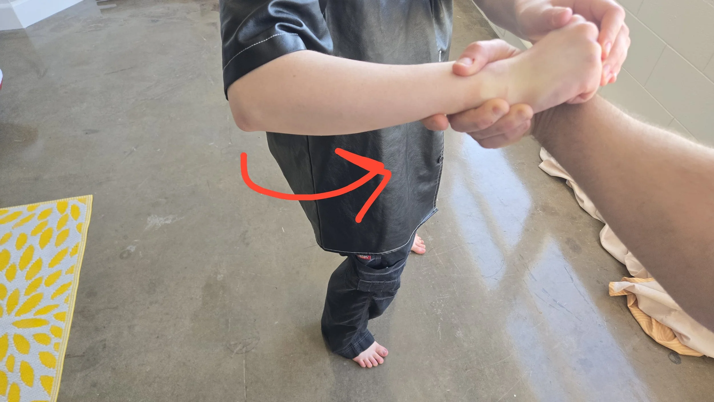 I am beginning to face away from the attacker without moving my feet. My hips are turning, and I amtwisting my wrist towards my chest. The man's hand is barely hanging on.