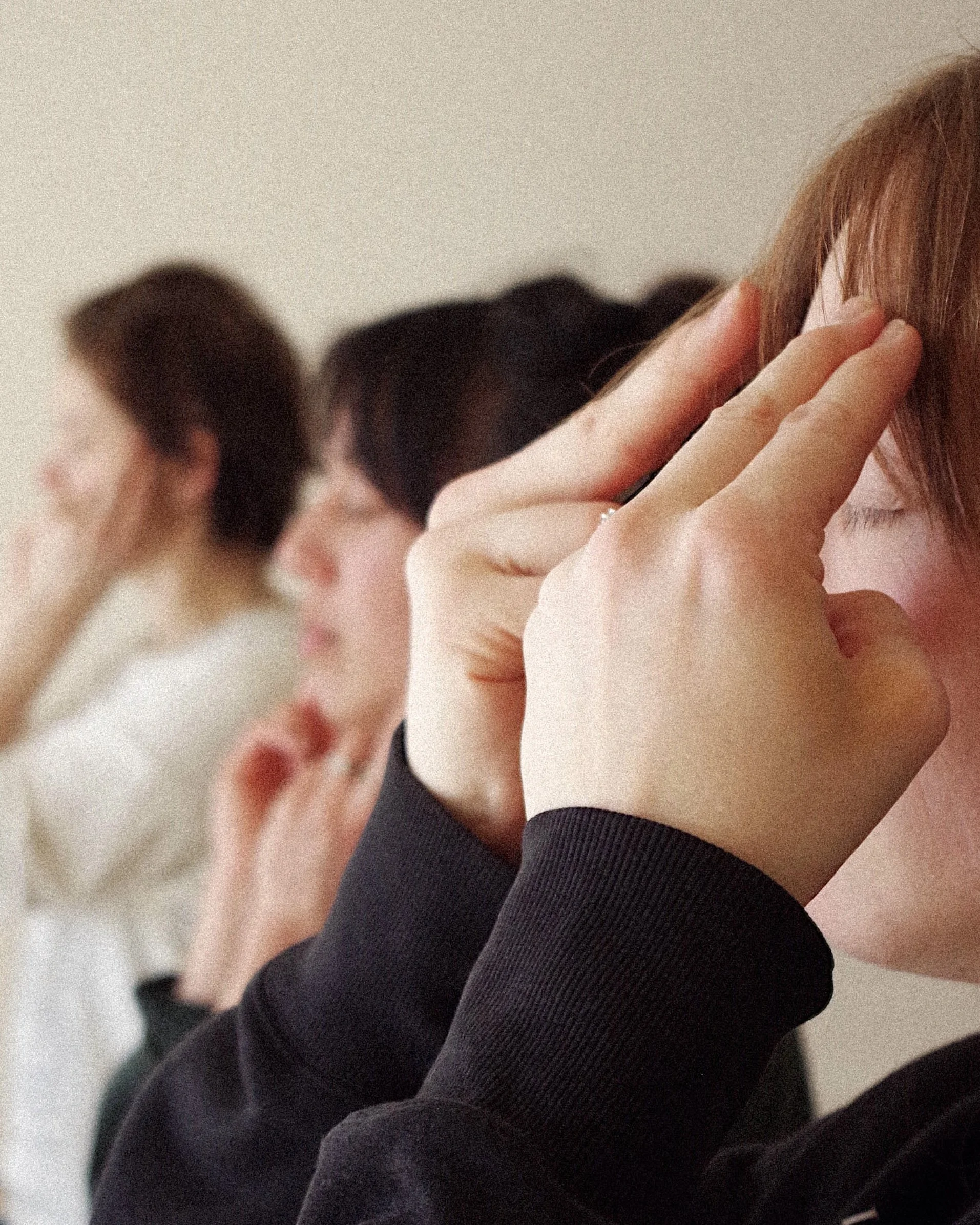Multiple people with eyes closed, holding fingers to their temples, suggesting concentration or stress.