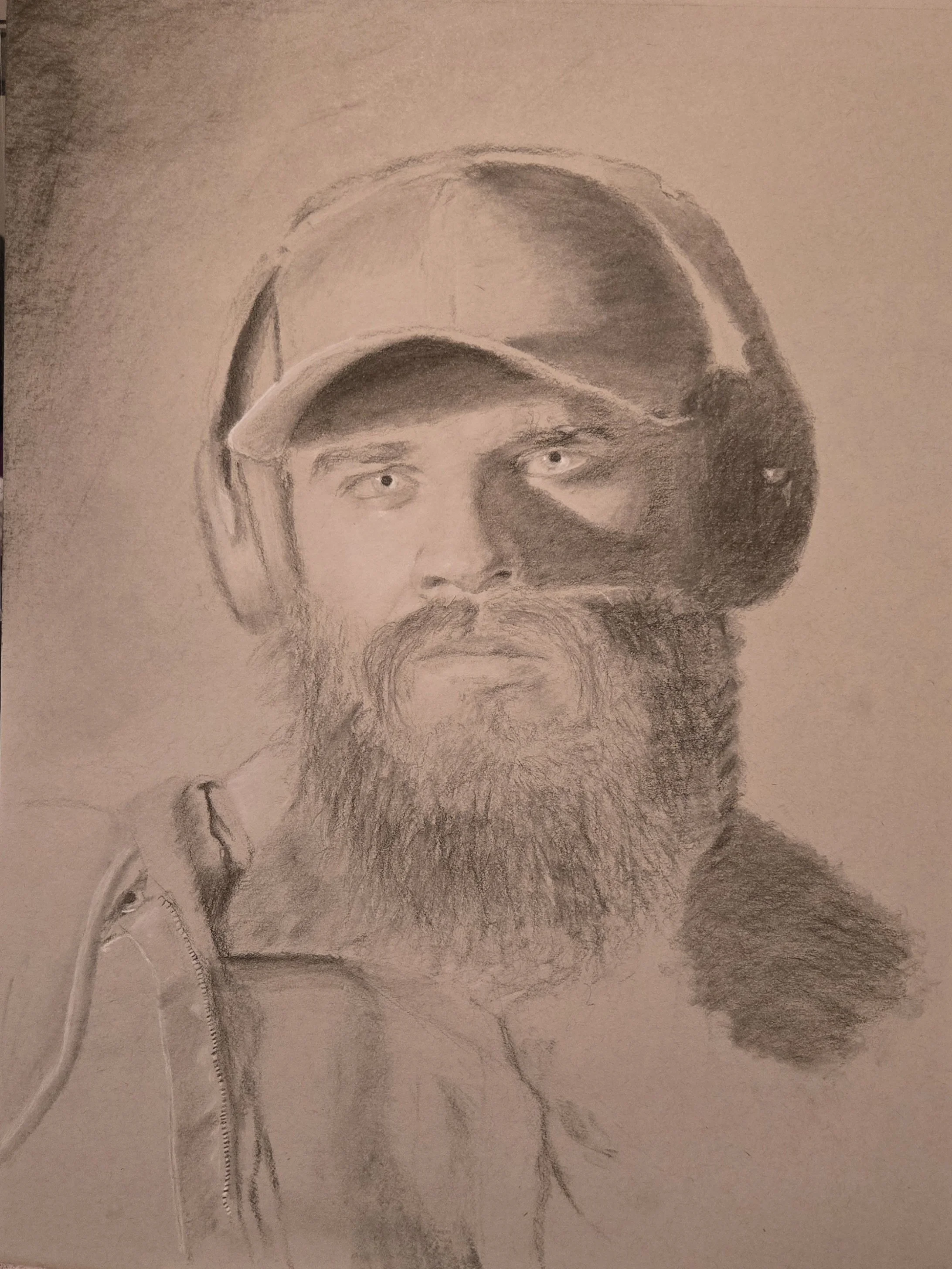 A detailed pencil sketch of a man with a beard, wearing a cap and headphones, with a serious expression.