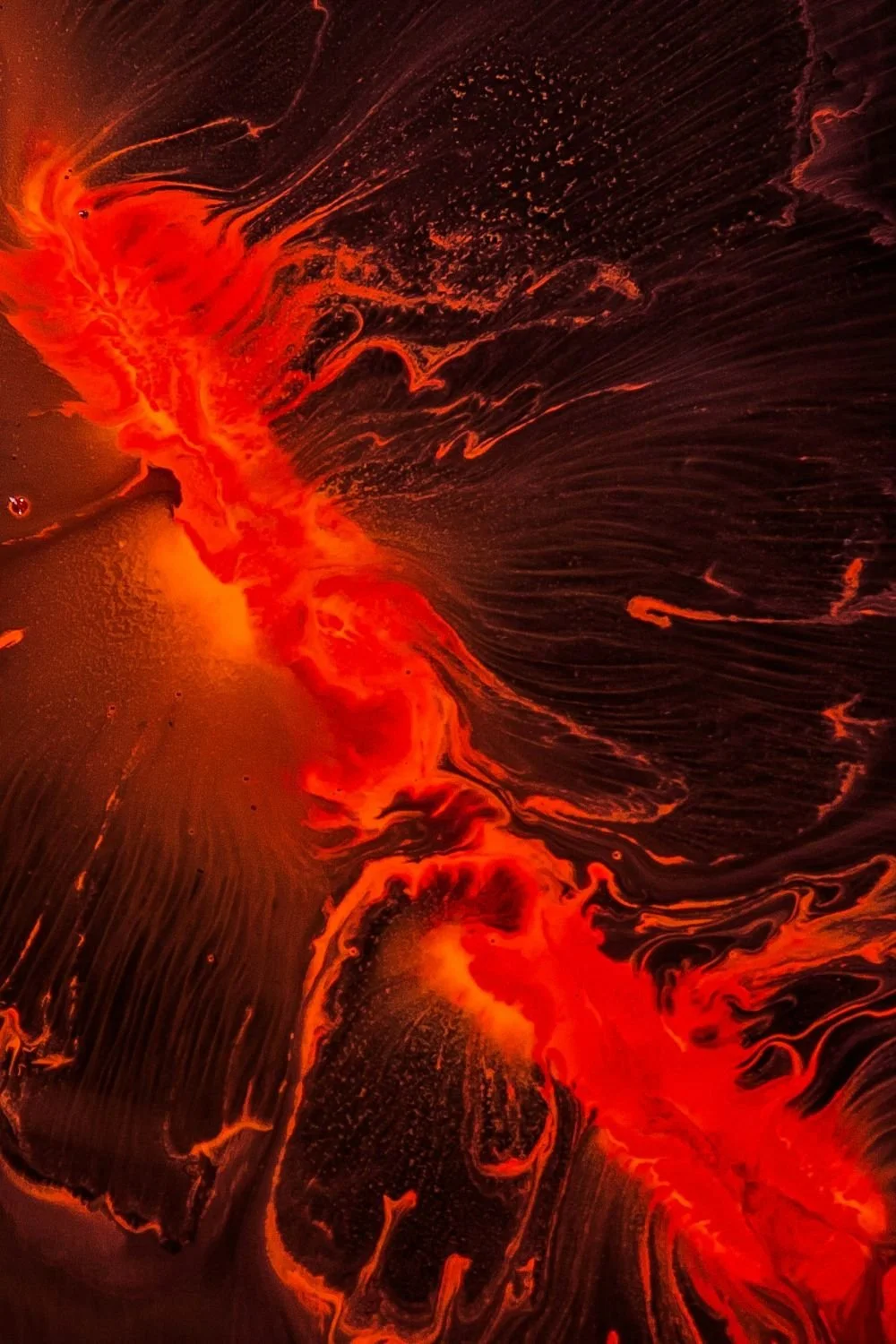 Abstract image with red and black swirling patterns, resembling a fiery explosion or volcanic eruption.