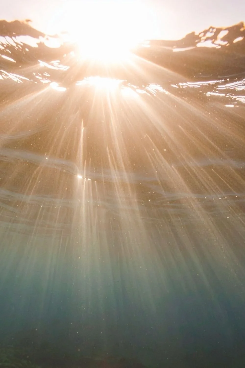 Sunlight shining through the water, creating rays and reflections.