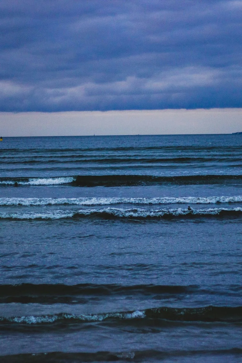 Image of the ocean with waves and a cloudy sky during dusk or dawn.