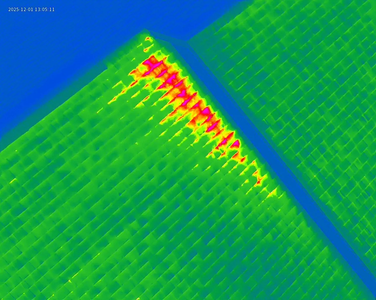 A thermal or infrared image showing heat distribution on a roof, with the hottest areas in pink and red along a diagonal edge, transitioning to cooler green and blue.