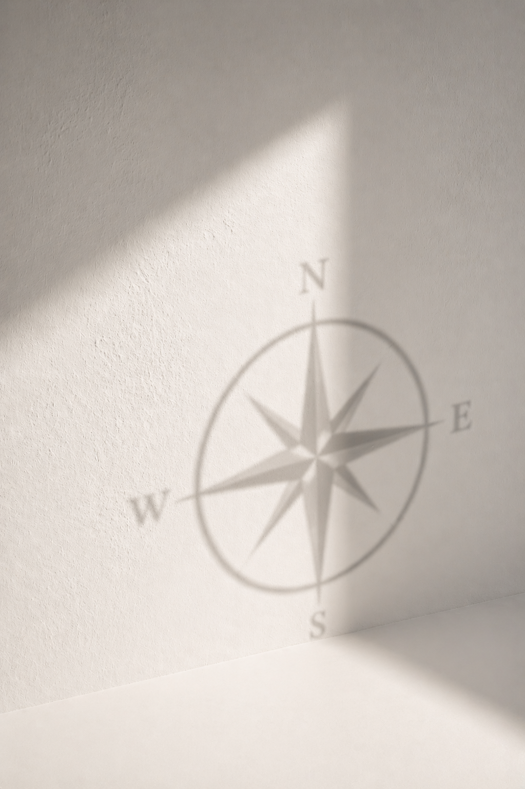 Shadow of a compass rose projected on a white wall, with sunlight creating the shadow.