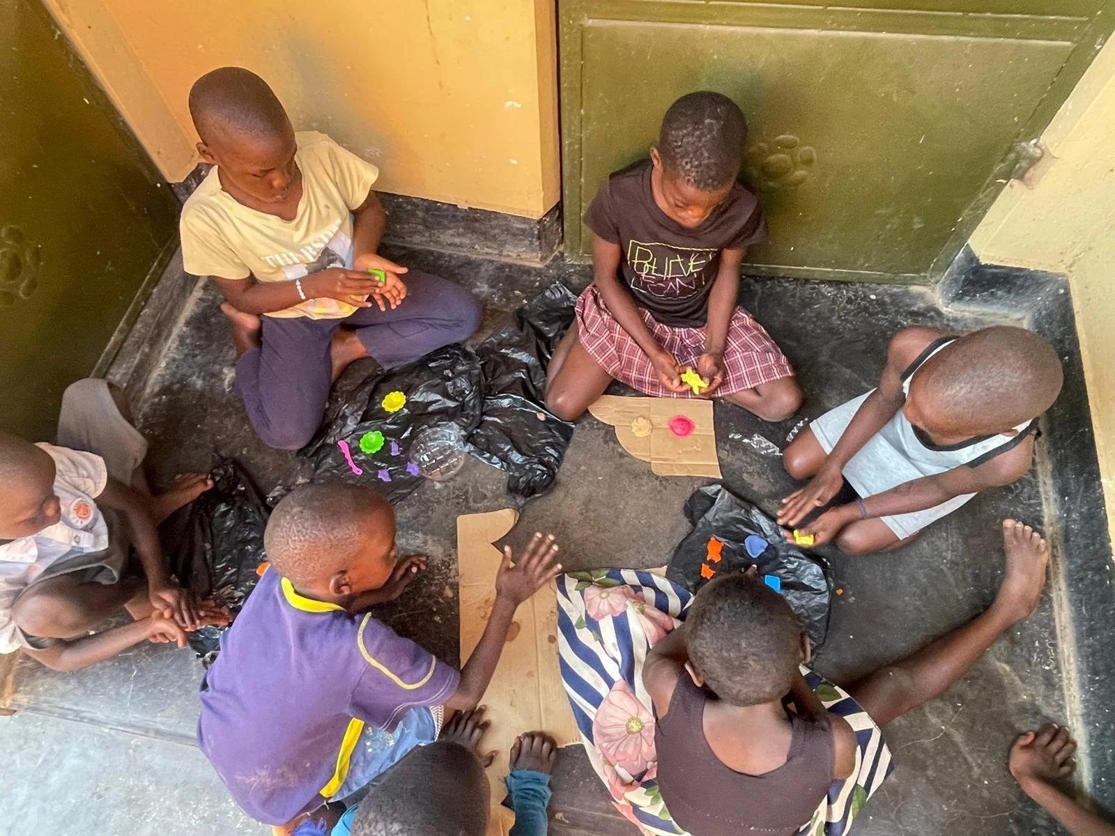 Children sitting on the floor in a circle, playing with colorful toys.
