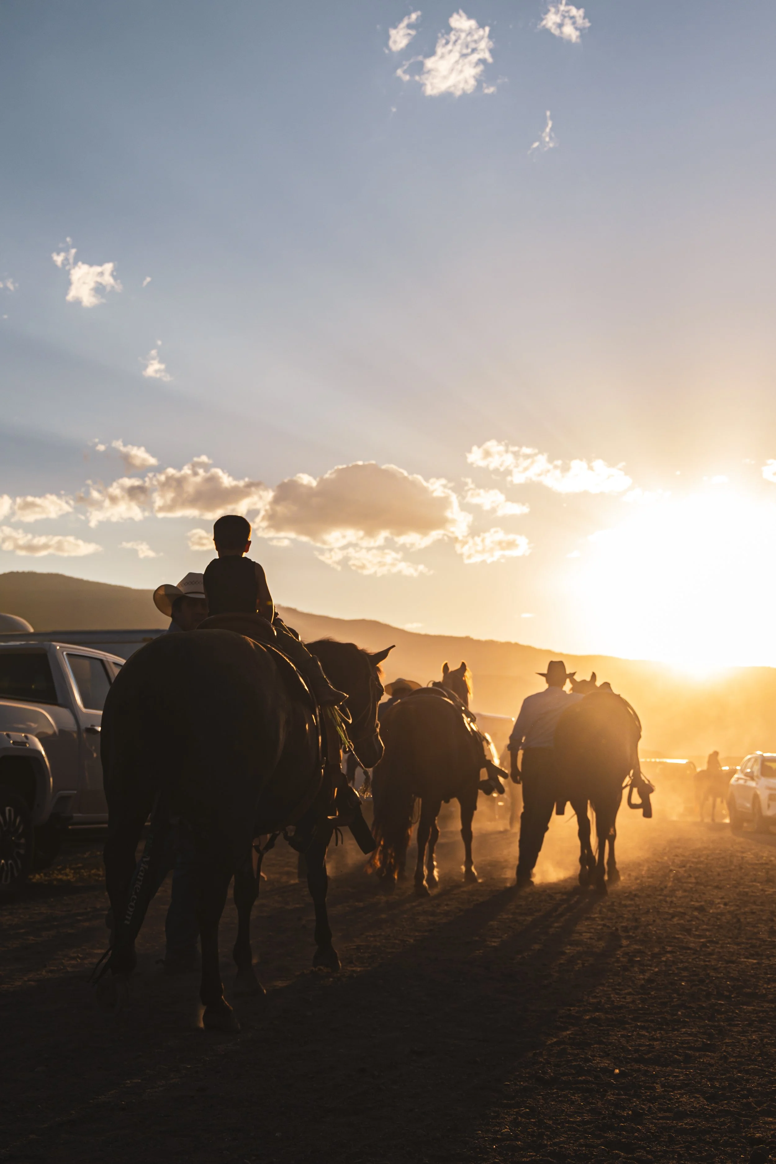 People riding horses at sunset with mountains in the distance.