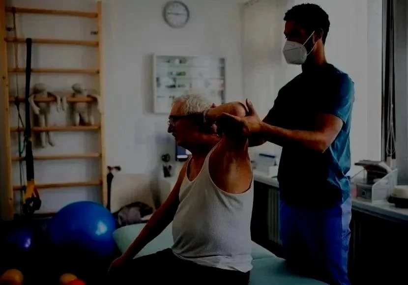Un homme âgé faisant de la physiothérapie avec un thérapeute dans un centre de rééducation, portant un masque