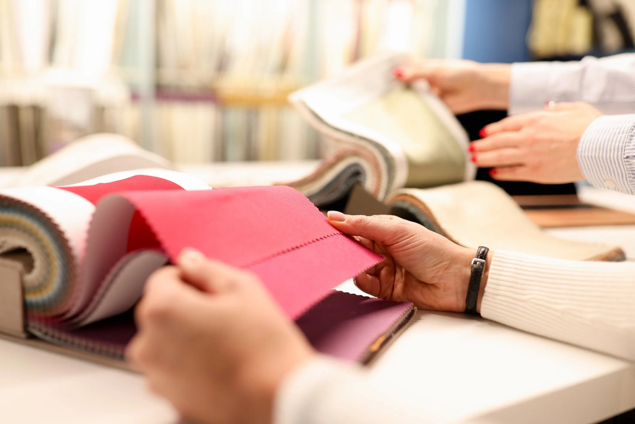 People shopping for fabric or upholstery samples, flipping through fabric swatches in a store.