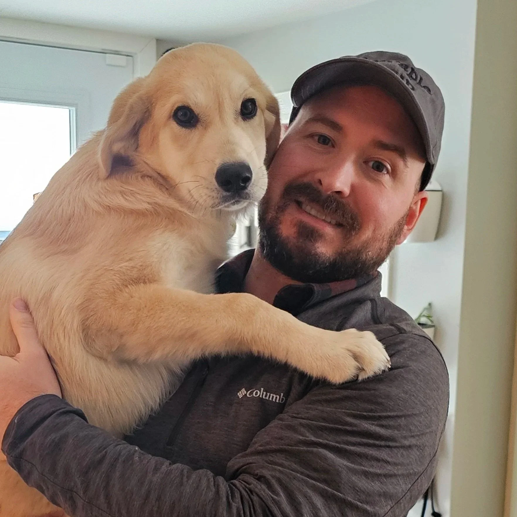 Headshot of Rob MacNeil smiling, holding his young dog.