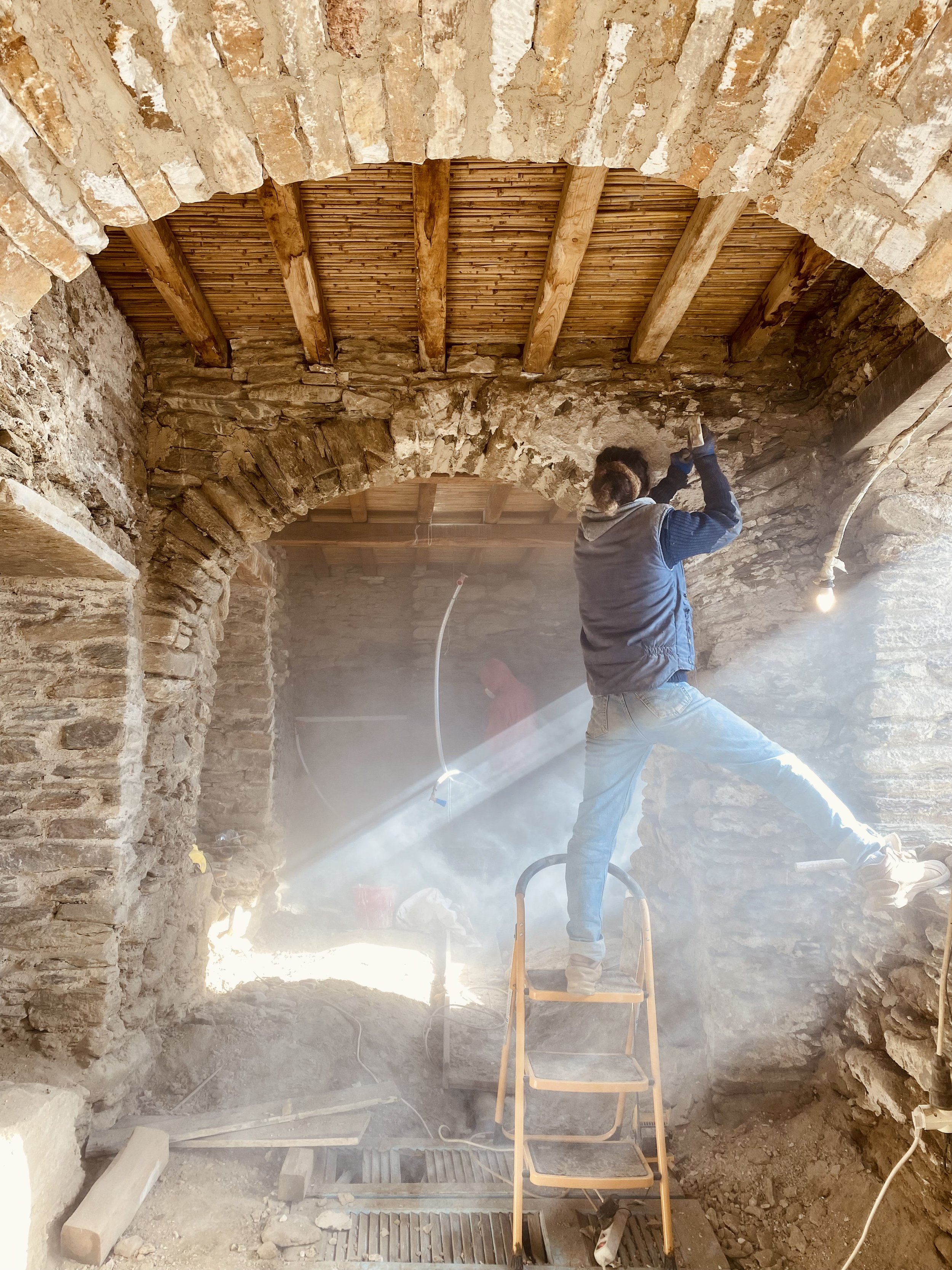 Chipping away old, cement plaster from stones