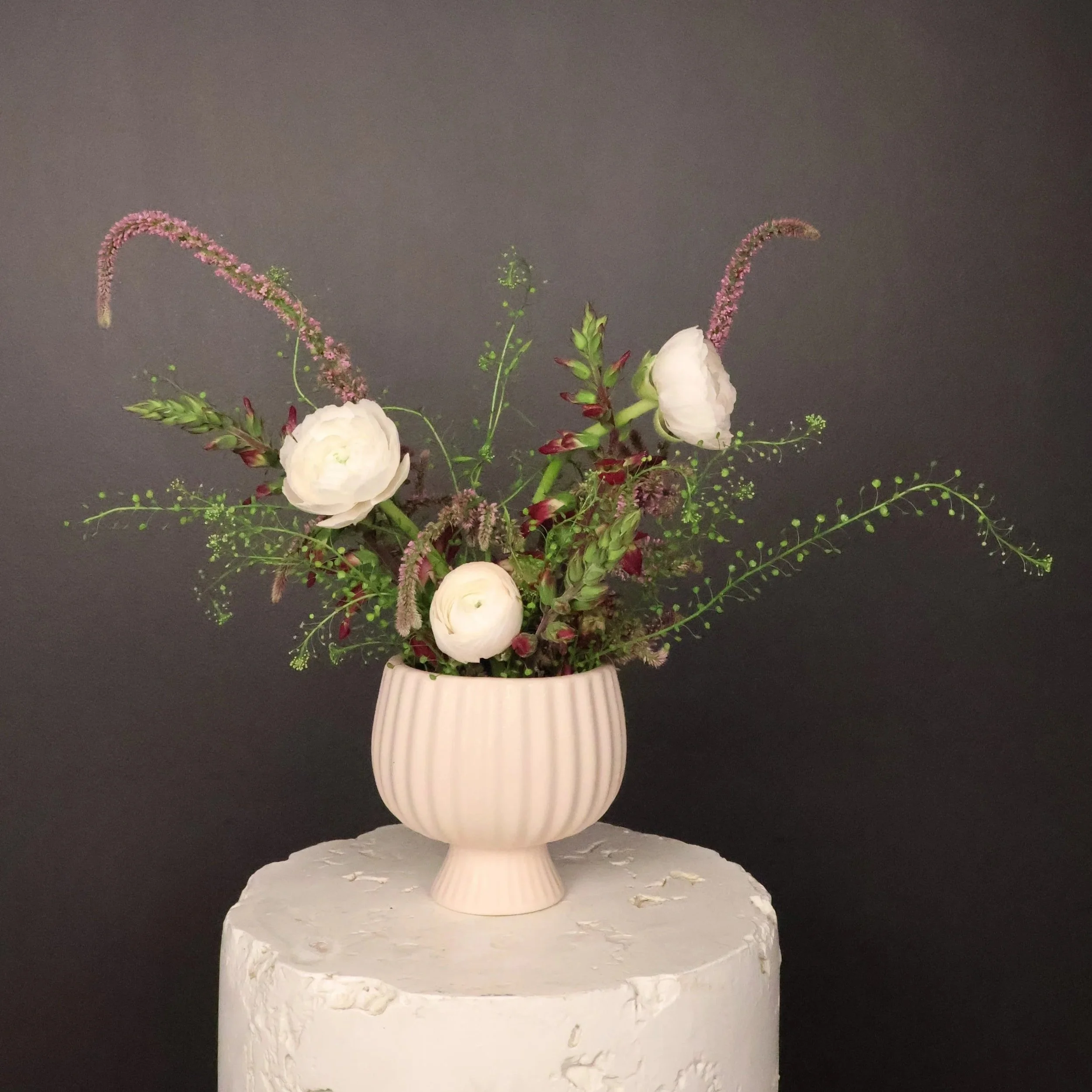 Luxury garden-style floral arrangement featuring white ranunculus, burgundy seasonal blooms, and airy greenery in a cream pedestal vase by Joon & Bloom, an Omaha florist.