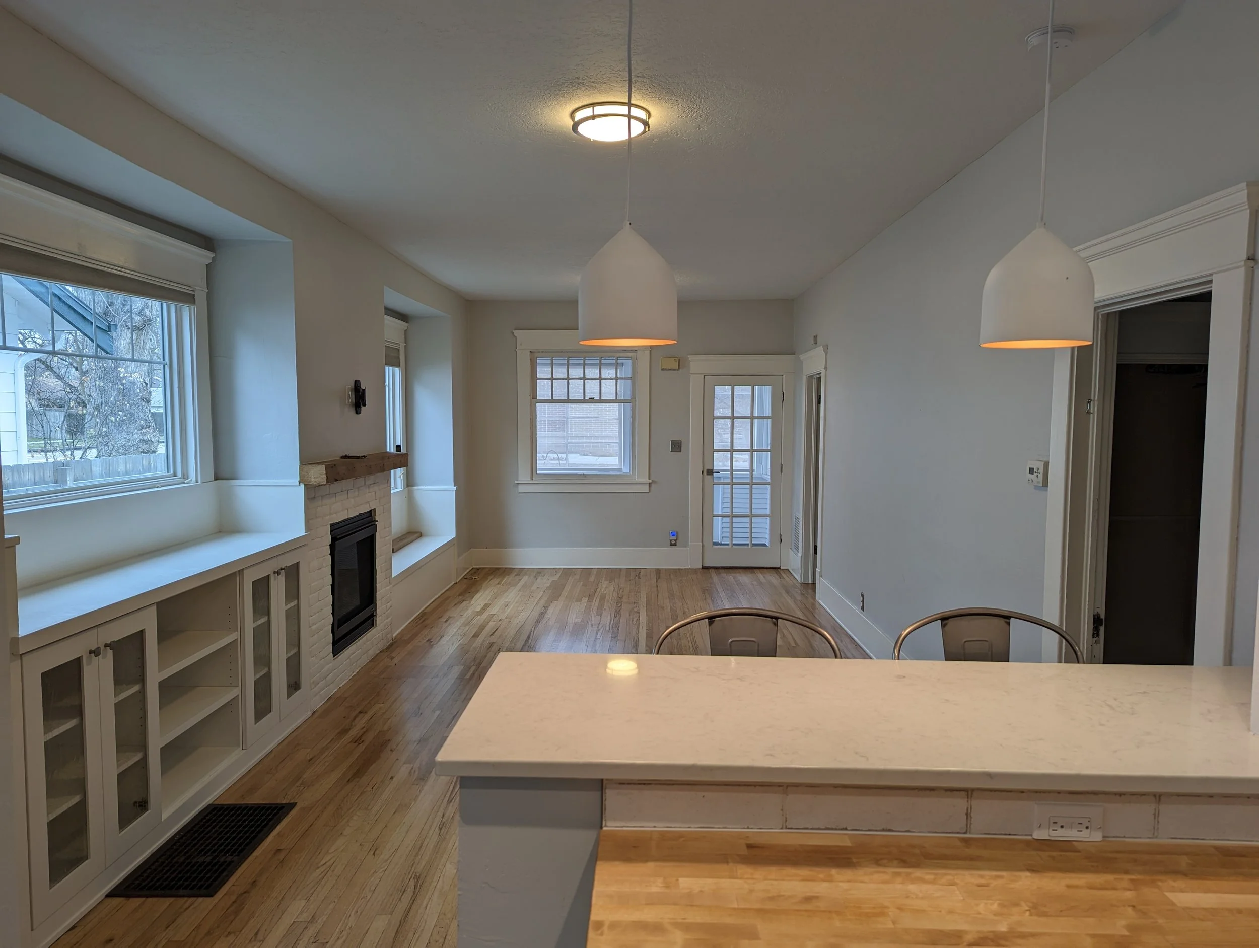 Open concept living room remodel in Boise Idaho featuring custom built-ins, fireplace, and modern lighting by residential builder